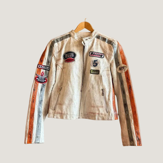 Vintage racing jacket with patches on a hanger against a brick wall