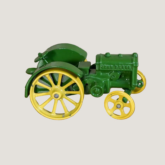 Green toy tractor with yellow wheels on a wooden surface